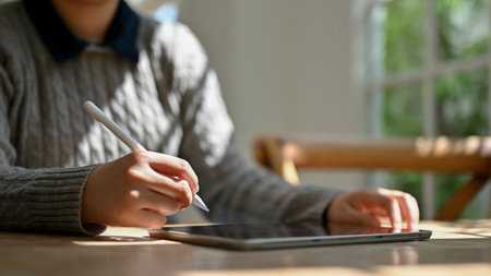 Cropped image of a female in cozy sweater using her digital tablet while relaxing in the cozy coffee shop. Lifestyle and technology conceptsの写真素材