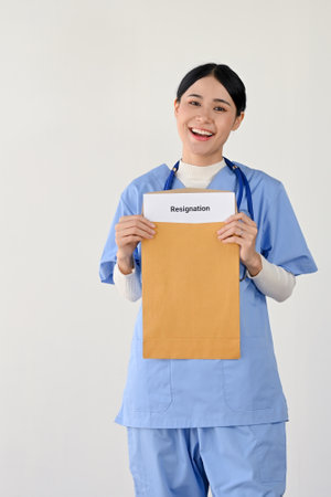 Portrait of a beautiful and cheerful young Asian female doctor or medical worker in scrubs holding...