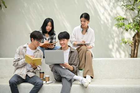 Group of young Asian college students sitting on a bench in a campus relaxation area, doing homework...