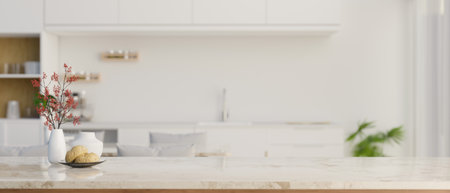 Close-up image of a copy space for your product display on a white marble tabletop over blurred background of a modern luxury white kitchen with dining table. 3d render, 3d illustrationの写真素材