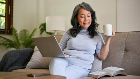 A beautiful and happy mature middle-aged Asian woman or businesswoman in casual clothes is working...