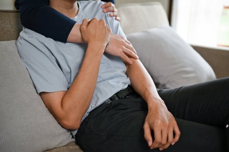 Cropped image of a happy gay couple hugging each other while watching a movie on a TV on a couch in the living room together. carefree and happy moment, LGBTQ+の写真素材
