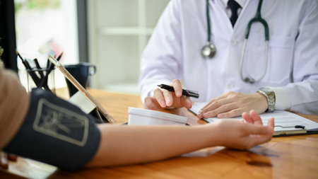 Close-up image of a professional male doctor examining a patient's heart rate and measuring blood pressure with a monitor in the hospital.の写真素材