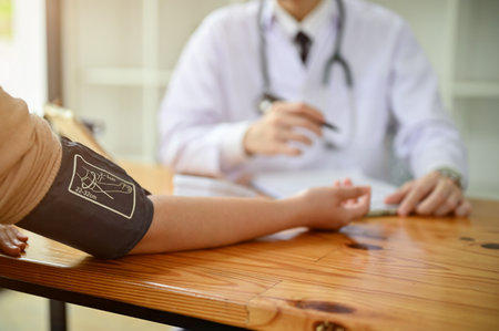Close-up hand image, A patient being checked up and measured blood pressure with a monitor by a doctor at the hospital.の写真素材