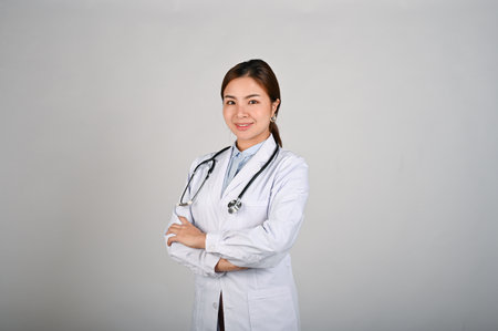 Portrait of young confident female doctor standing with white isolated background.の写真素材