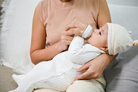 Mother holding and feeding baby from milk bottle. Portrait of cute newborn baby being fed by her mother using bottle.の写真素材