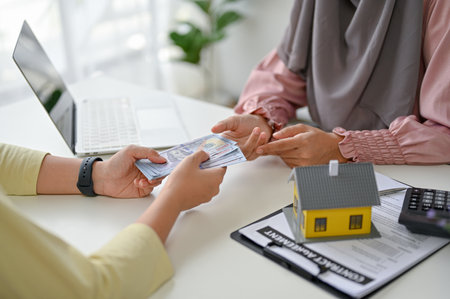 Young professional muslim real estate agent receiving money from her client. Close-up imageの写真素材