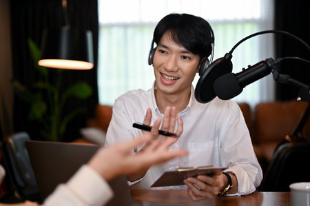 Radio DJ or podcast artist wearing and headset interviewing guest in recording studio. radio podcast, influencer, live streamの写真素材