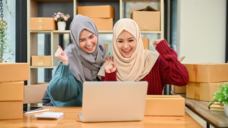 Young Muslim team of online business celebrating together after receiving big orders or getting good feedback on the shopping website.の写真素材
