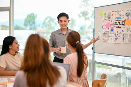 A professional Asian male tech developer is presenting his project to his colleagues in the meeting. consulting, brainstorming, working togetherの写真素材