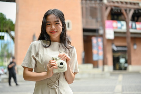 A portrait of a charming young Asian woman in casual clothes strolling around the city with her...