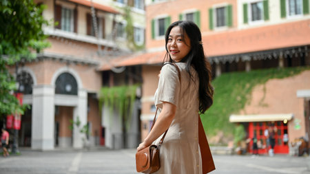 An attractive young Asian woman in casual clothes enjoys strolling in the city alone on her weekend....