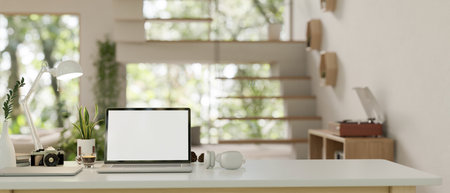 A modern home office workspace with a laptop white screen mockup, modern headphones, a camera, and...
