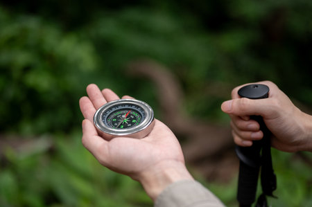 Close-up image of a male hiker holding a compass while hiking in the forrest alone. direction,...