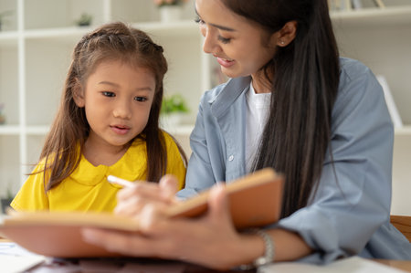 An adorable little Asian girl is focusing on studying with a kind private teacher at home....