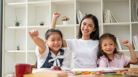 A happy and cheerful young Asian female babysitter or private teacher is enjoying the art class together. children, kindergarten kids, elementary school studentsの写真素材