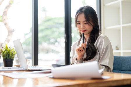 A beautiful and professional Asian businesswoman is focusing on her work at her desk in the office.の写真素材
