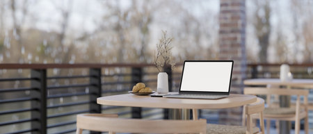 A laptop white screen mockup on a wooden table on a balcony or terrace in the winter of a cosy coffee shop or restaurant. close-up image. 3d render, 3d illustrationの写真素材