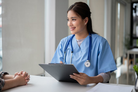 A beautiful and professional Asian female doctor is talking, counseling, and diagnosing the disease of a patient in an examination room at a hospital. Medical checkup, Health careの写真素材