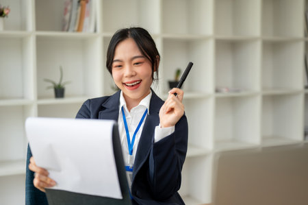 A beautiful and cheerful Asian businesswoman is examining a business report in her office. banker, lawyer, secretary, manager, accountantの写真素材