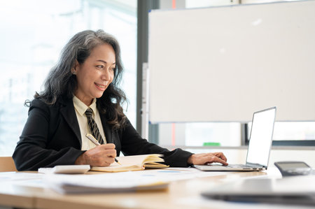 A professional and elegant senior Asian businesswoman or female executive manager working on her...