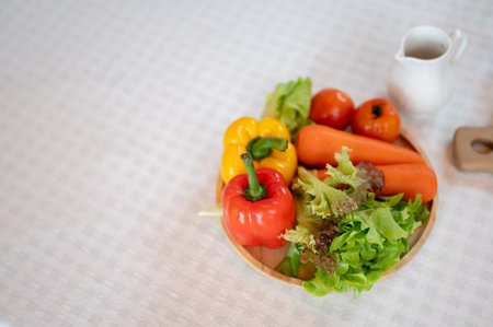 A plate of fresh vegetables on a dining table. Sweet peppers, carrots, tomatoes, and green lettuce. Home cooking conceptの写真素材