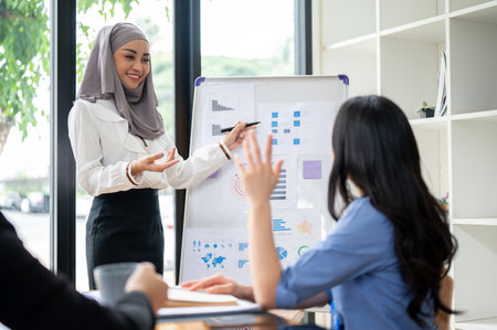A confident and professional Asian Muslim businesswoman or female leader let everyone in the meeting ask her questions after she finished her presentation.の写真素材