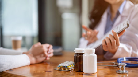 Close-up image of two bottles of medicine, pills, and a stethoscope on a table in a doctor's...