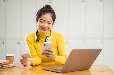 A beautiful and happy young Asian woman using a mobile banking application to transfer her money or...