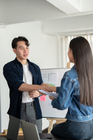 A handsome and professional young Asian businessman is shaking hands with a female colleague in the meeting. teamwork conceptの写真素材