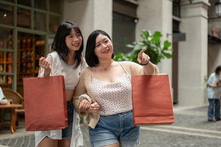 Two cheerful young Asian female friends are enjoying walking in the shopping mall and enjoying their shopping spree day. Lifestyle conceptの写真素材