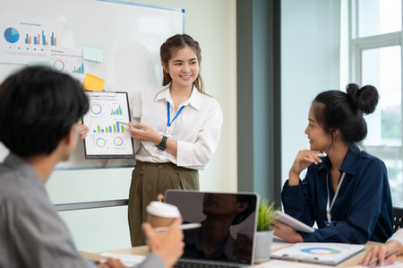 Young energetic businesswoman presenting her project to her coworkers during the meeting in the office room. Business concept.の写真素材