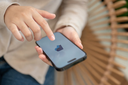 Chiang mai, Thailand - Oct 04 2023: A woman sitting indoors and using a PayPal application through her Iphone14. A PayPal logo on an Iphone14 screen.のeditorial素材