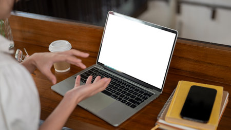 Close-up image of a woman working remotely at a coffee shop, having an online meeting with her team,...