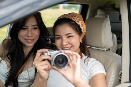 A happy and attractive young Asian girl is taking pictures with her camera during her road trip...