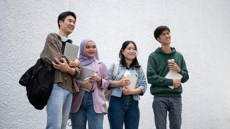 A group of happy, diverse young Asian college students in casual clothes are standing outdoors together. University life, friendship, educationの写真素材