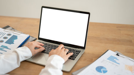 Close-up image of a businesswoman using her laptop, responding to emails, working at her desk. A white-screen laptop mockup.の写真素材
