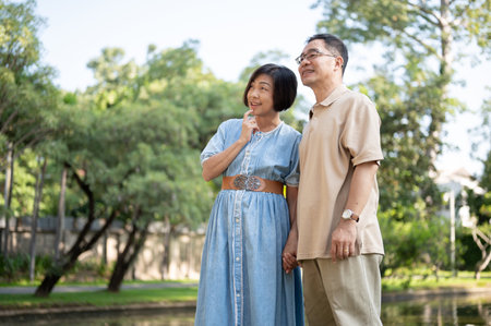 Happy retired senior Asian couples are strolling around a public park on the weekend together. Leisure, happy marriage, healthy relationshipの写真素材