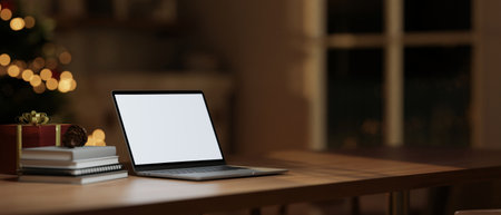 A white-screen laptop mockup, books, and a gift box on a wooden table in a cosy living room on a Christmas night. 3d render, 3d illustrationの写真素材