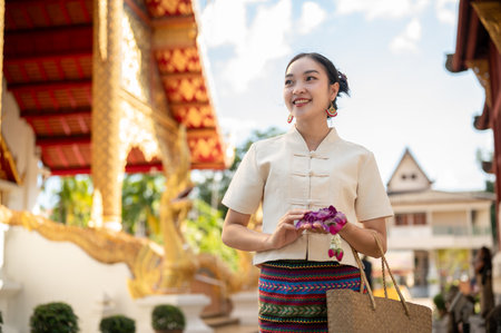 A charming and beautiful Thai-Asian lady in a beautiful traditional Thai-Northern dress is visiting a temple on a Buddhist holy day to pay respect to Buddha and make a merit. Thai culture, Buddhismの写真素材
