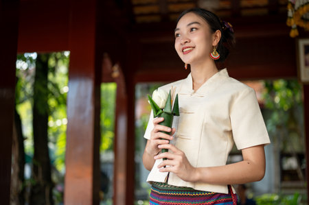 A beautiful Thai-Asian woman in a beautiful traditional Thai-Lanna dress with a flower for pay respect to the image of the Buddha in a temple. Thai-Lanna culture, Buddhistの写真素材