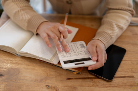 Close-up image of a woman using a calculator, checking her income and expenses and planning her...