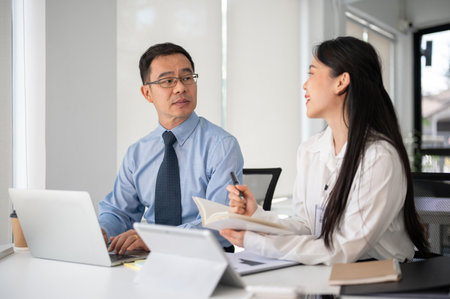 Young motivated businesswoman working with experience senior businessman in the white modern office room. Businesspeople concept.の写真素材