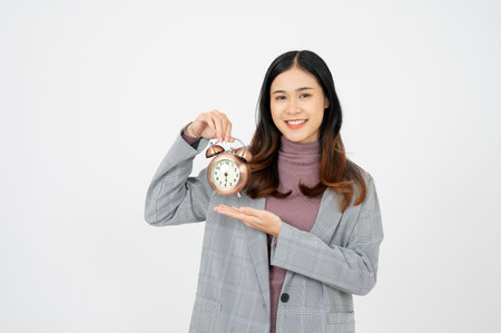 Smiling asian businesswoman holding clock and looking at the camera over white background.Time management concept.の写真素材