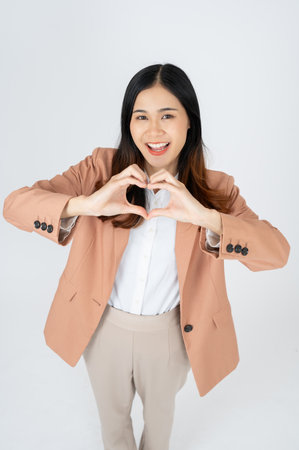 Beautiful smiling Asian businesswoman making heart shape hand sign on white isolated background.の写真素材