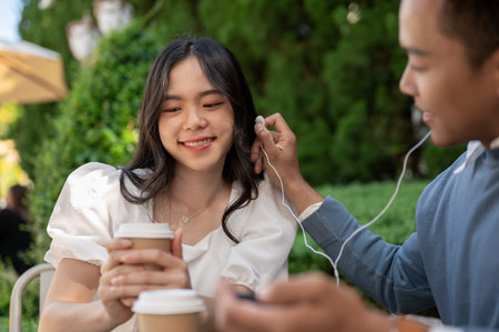 Young Asian couple listening to music together, having fun together in the green park. Couple concept.の写真素材