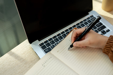 Close-up top view image of a woman writing something in her book, working remotely at a coffee shop...
