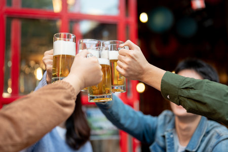 Group of cheerful young Asian friends are cheering, toasting, clinking, or enjoying beer at a restaurant or bar in the city on the weekend together. Lifestyle and friendship concepts. close-up imageの写真素材