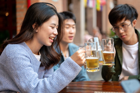 Group of happy young Asian friends are enjoying drinking beers and talking at a bar or restaurant in...