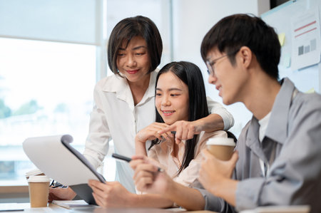 Group of cheerful diverse Asian businesspeople are in the meeting, checking a new project details in reports together. Teamwork, team building, co-working, brainstormingの写真素材